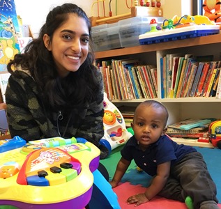 Volunteer playing with child in CMC child care.